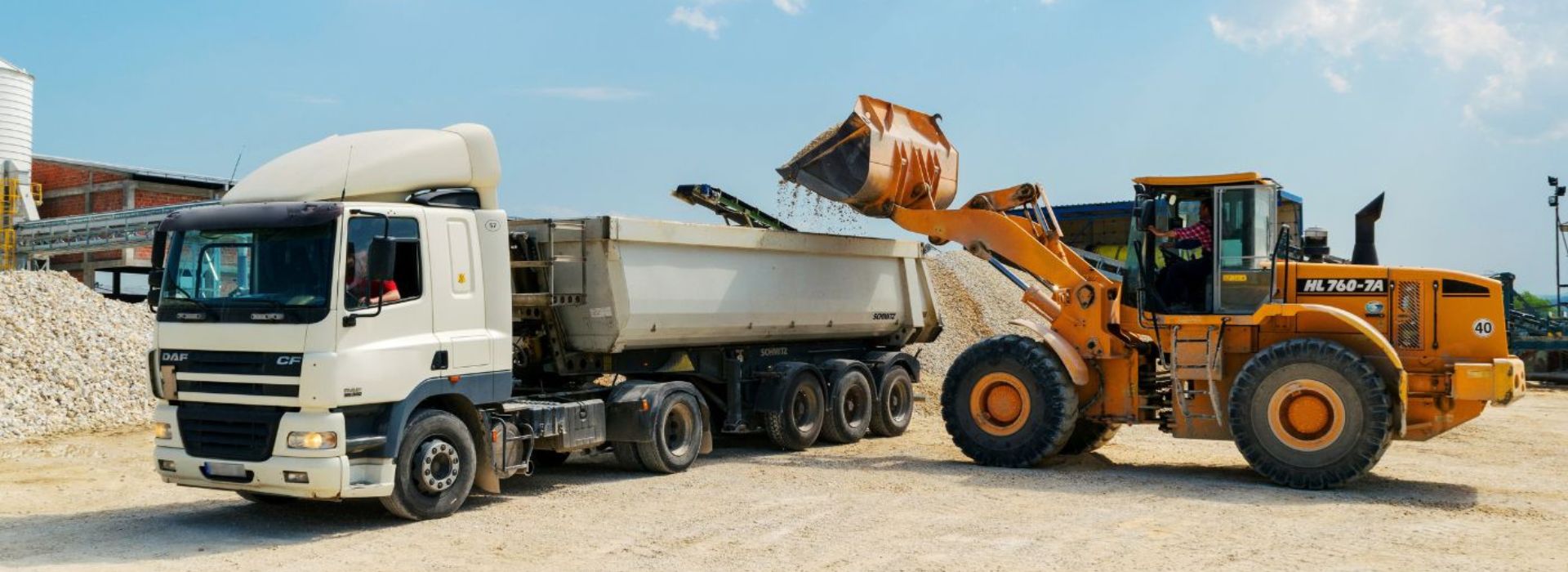 bulldozer dumping materials into a receiving truck.