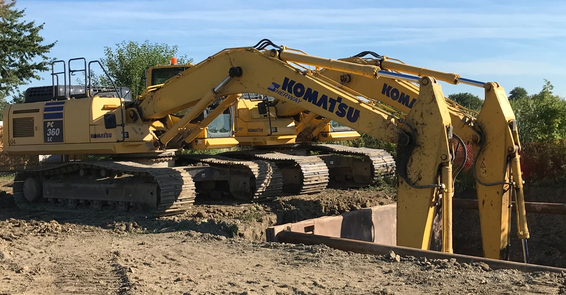 two excavators digging a large hole for underground construction.